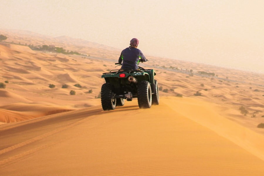 a person on a quad bike driving through the desert