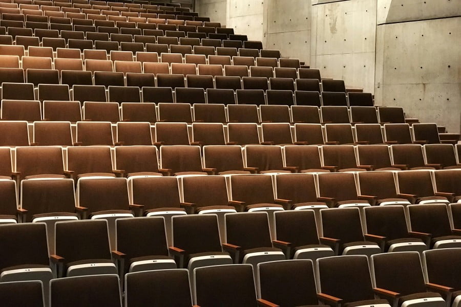 a rows of brown chairs in a auditorium
