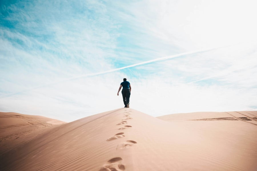 a man walking up a sand dune