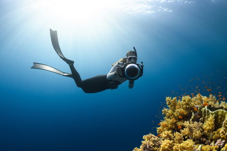 Diving a woman underwater with a camera