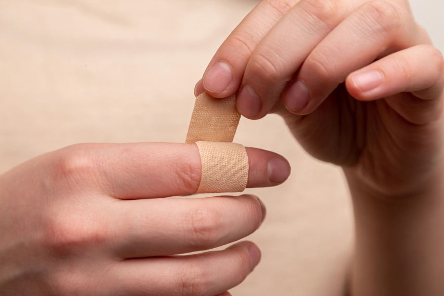 First Aid a person putting a band aid on a finger