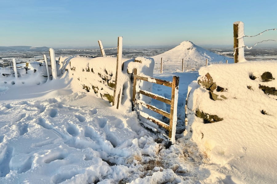 a snowy fence with a hill in the background