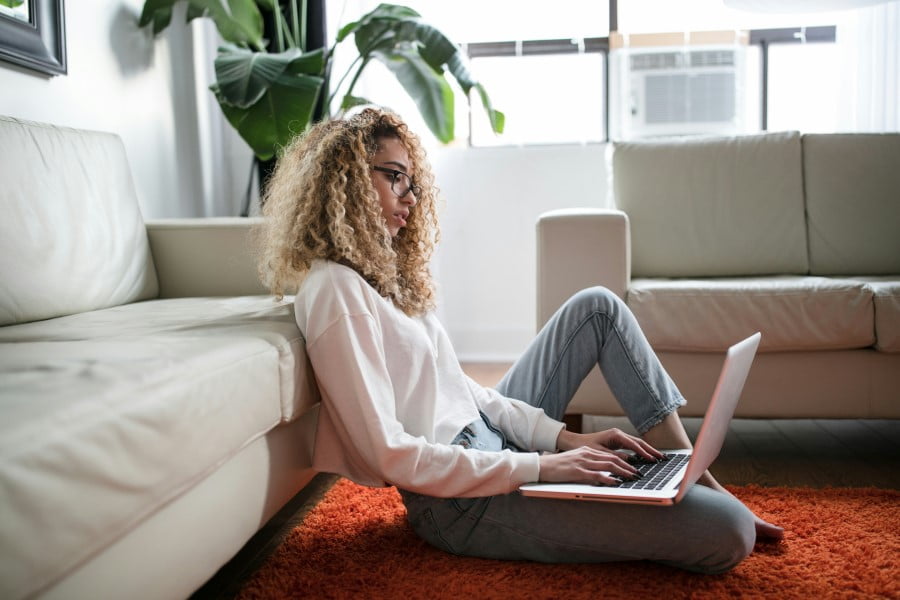 a woman sitting on the floor with a laptop